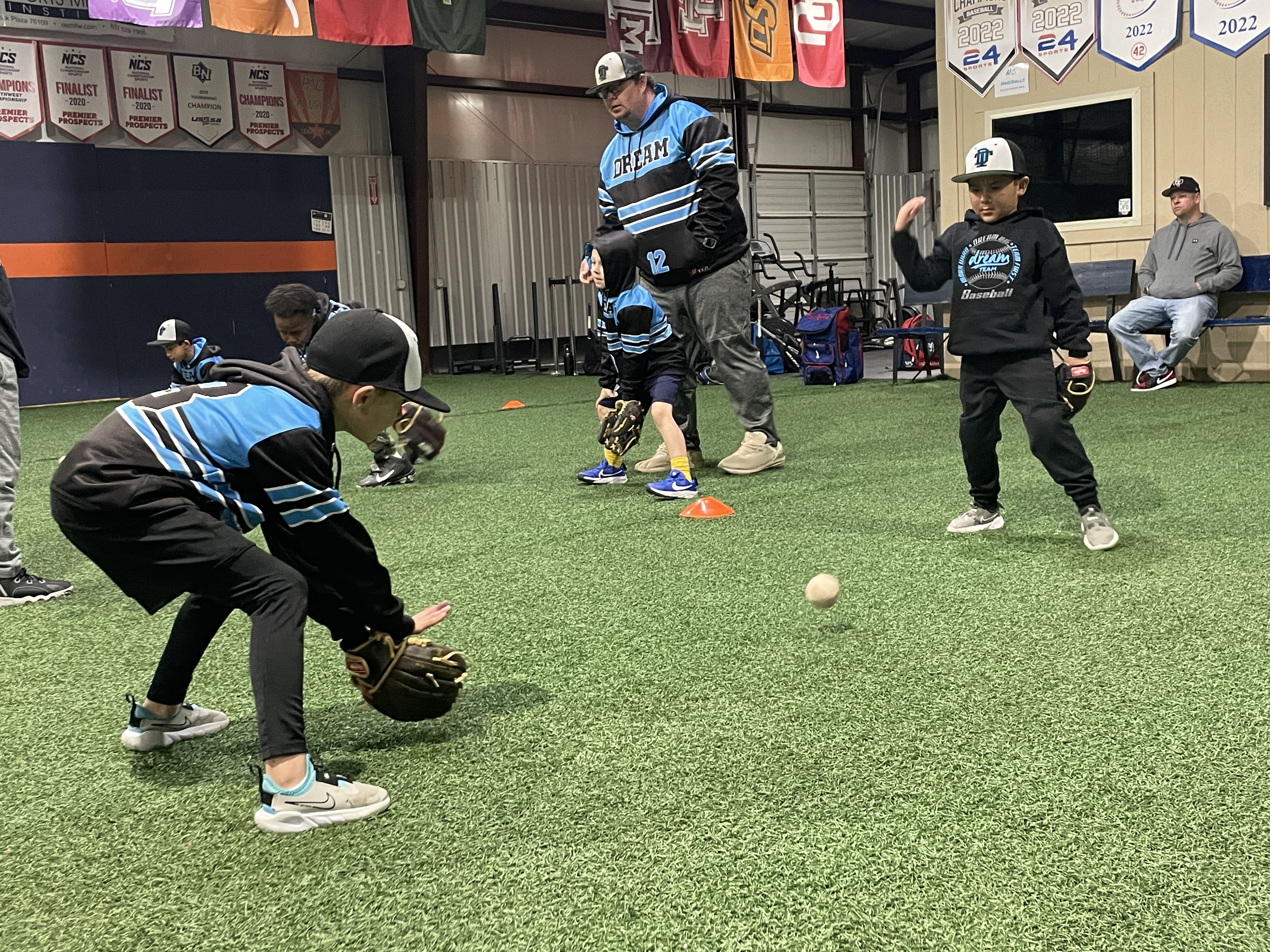 Patrick working with young baseball players during an indoor fielding drill