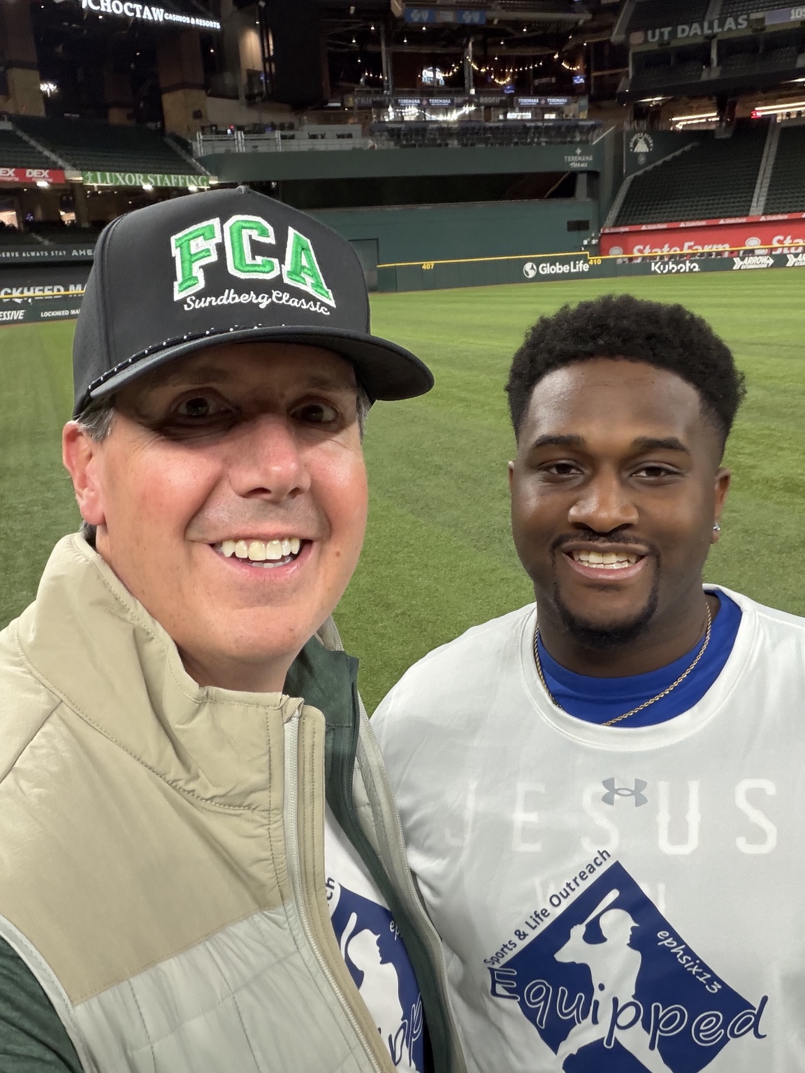 Patrick wearing an FCA cap with a fellow participant in a baseball stadium