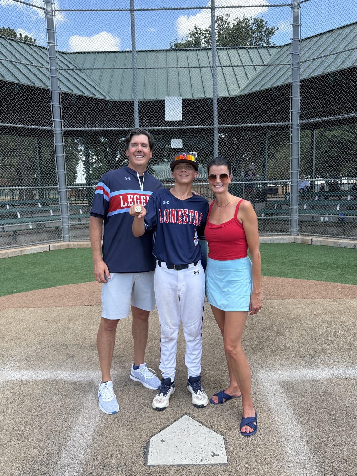 Patrick with a baseball player and another adult at home plate